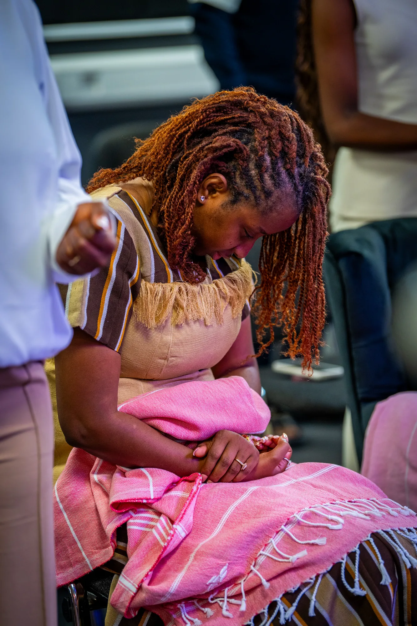 A seated congregation member with her head bowed and hands clasped